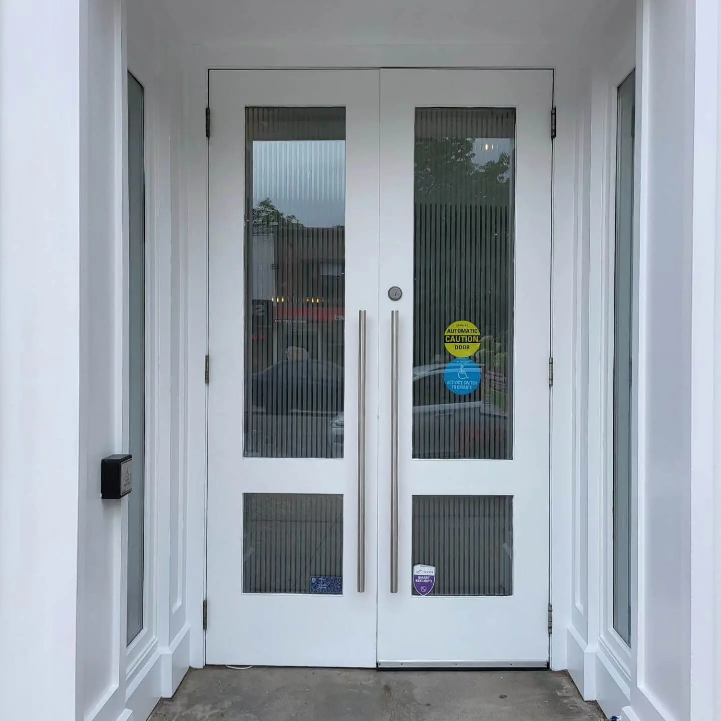 A close-up of double glass doors with vertical lines and metal handles, featuring caution signage. A close-up of double glass doors with vertical lines and metal handles, featuring caution signage.