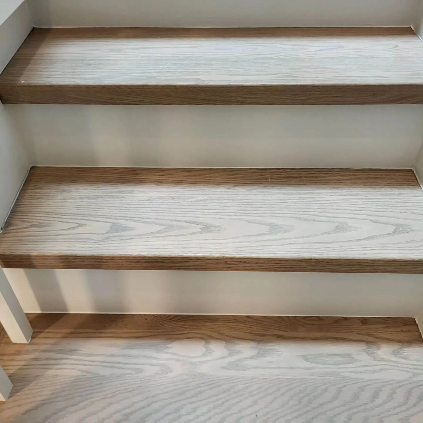 Detailed view of staircase treads with natural wood grain and white risers for a sleek finish. Detailed view of staircase treads with natural wood grain and white risers for a sleek finish.