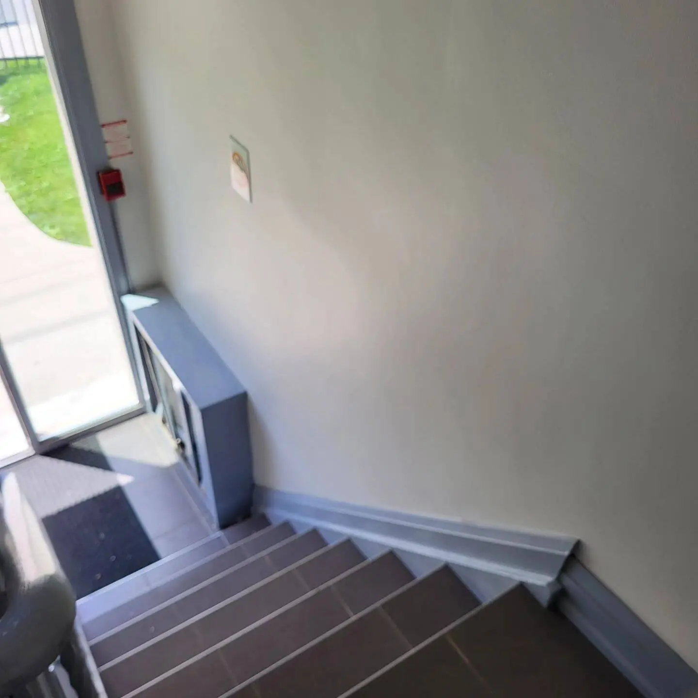 Downward view of tiled stairs near a glass door, showing a green lawn outside. Downward view of tiled stairs near a glass door, showing a green lawn outside.