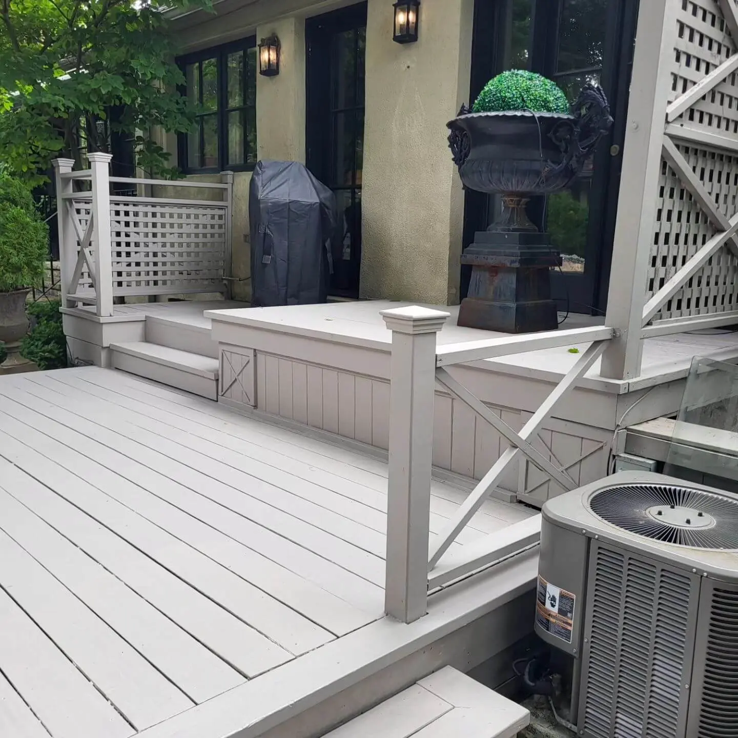 Elevated view of a deck with gray wood, a lattice railing, and a nearby air conditioning unit. Elevated view of a deck with gray wood, a lattice railing, and a nearby air conditioning unit.